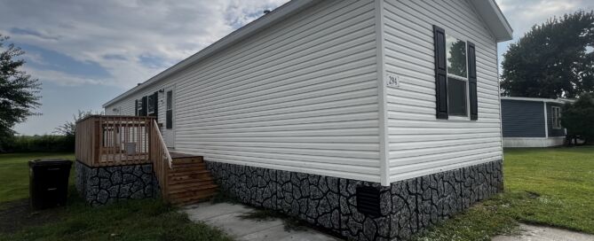 White siding and grey vinyl rock skirting